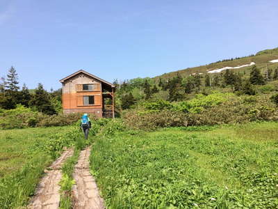 草原に立つ三ﾂ石山荘 